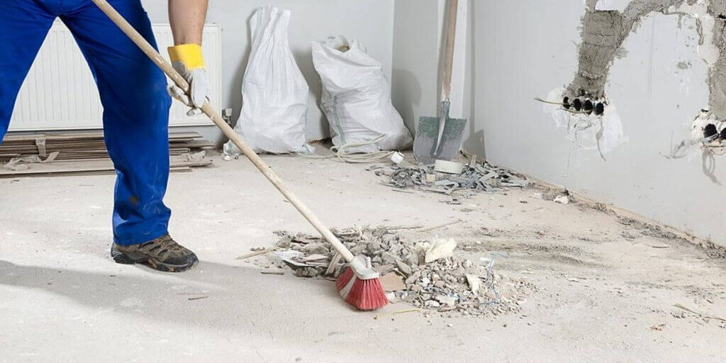man cleaning rubble from floor with broom