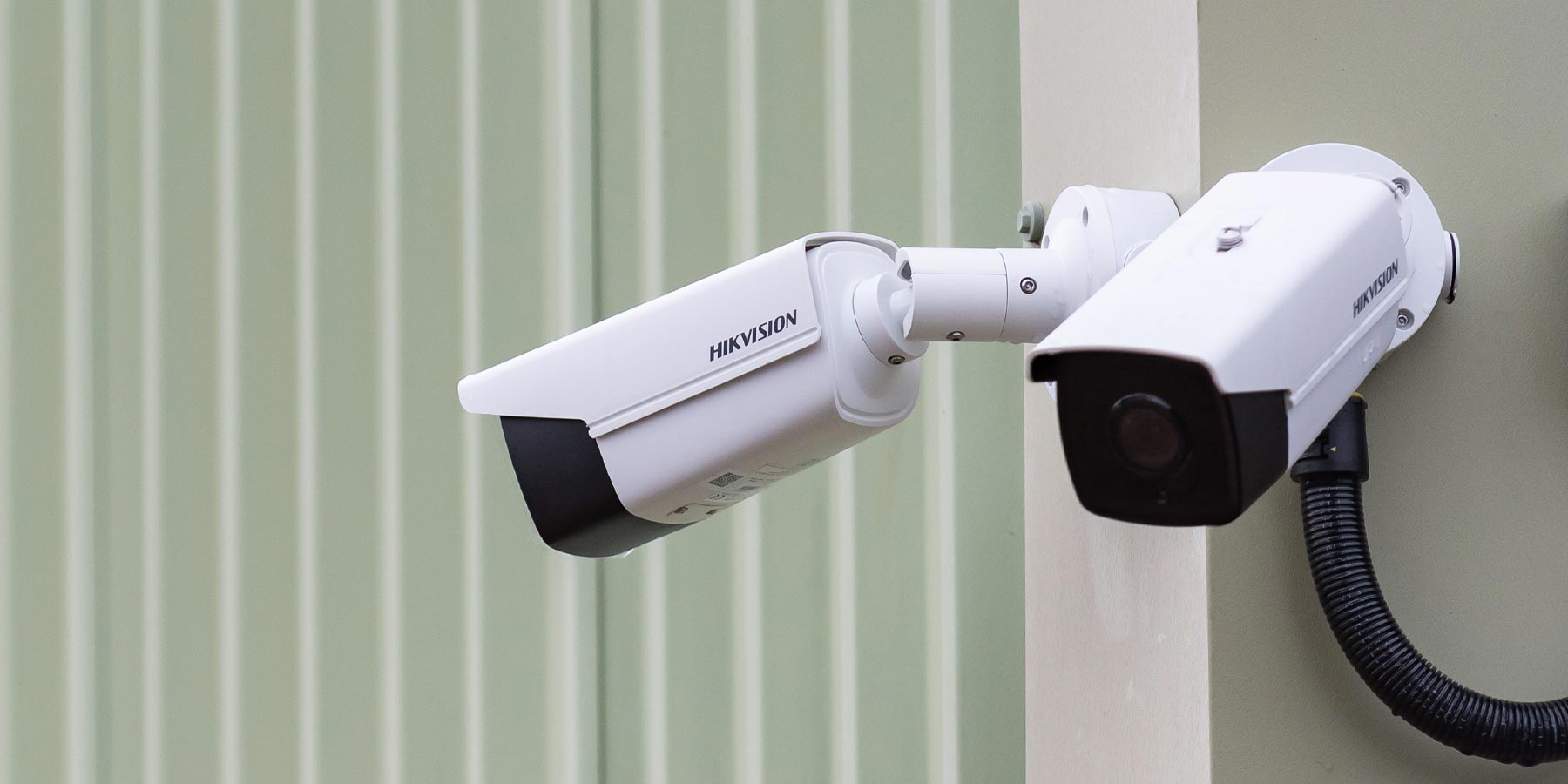 two CTS security cctv cameras with green industrial building behind